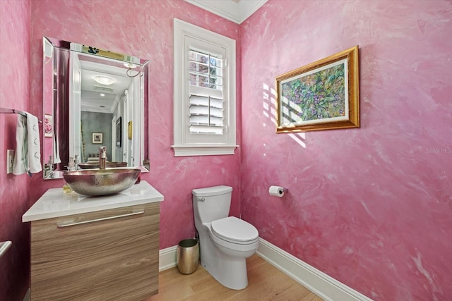 bathroom with wood-type flooring, vanity, toilet, and crown molding