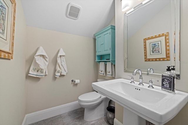 bathroom with toilet, vaulted ceiling, and sink