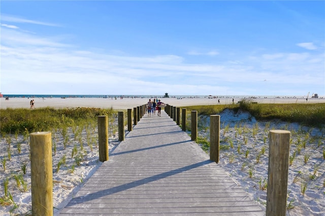 view of dock featuring a beach view and a water view