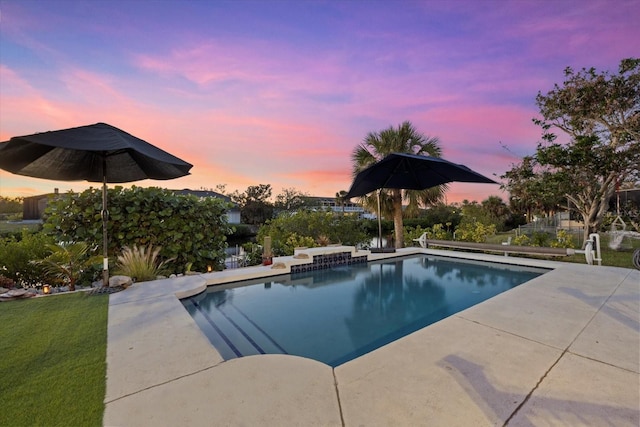 pool at dusk featuring a patio area