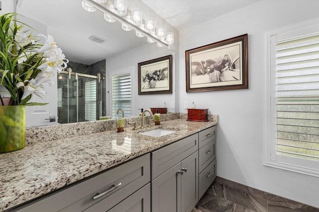 bathroom with a shower with door, vanity, and a healthy amount of sunlight