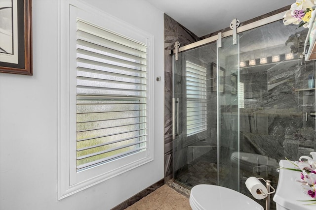 bathroom featuring toilet and a shower with door