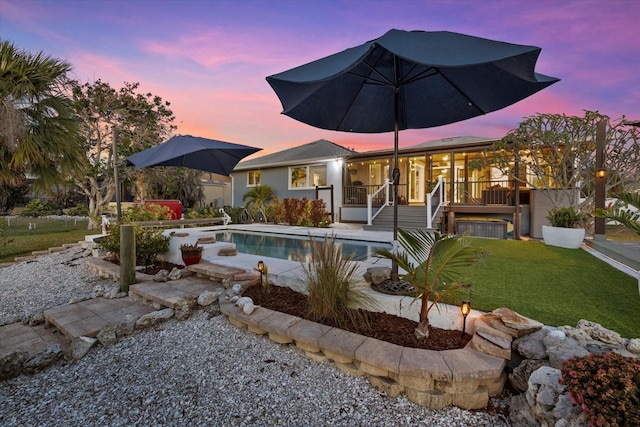 pool at dusk featuring a yard