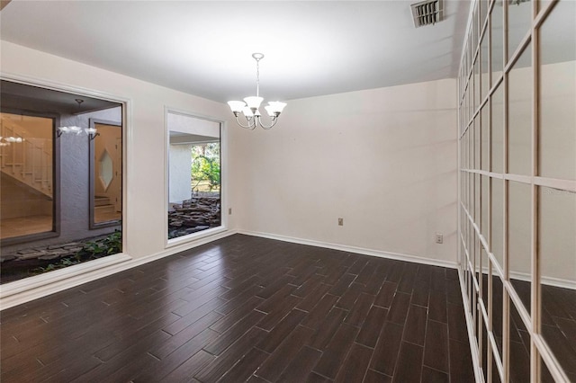 empty room featuring a chandelier and dark hardwood / wood-style floors