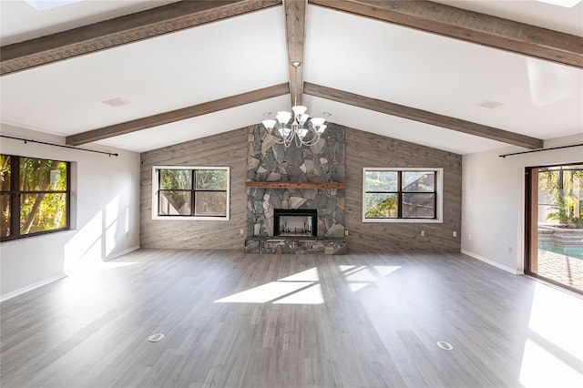 unfurnished living room with vaulted ceiling with beams, wood-type flooring, a stone fireplace, and a notable chandelier