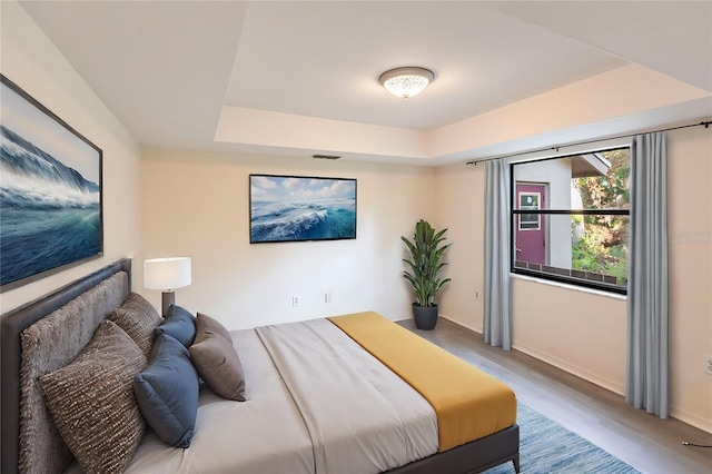 bedroom featuring a tray ceiling and hardwood / wood-style floors