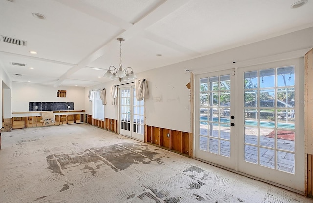 unfurnished living room with wood walls, an inviting chandelier, and french doors