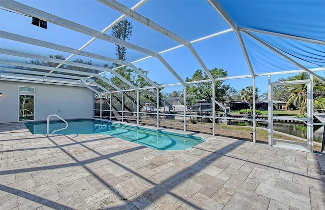 view of swimming pool featuring glass enclosure, a patio area, and a water view