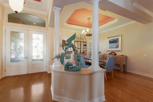 office area with decorative columns, a tray ceiling, crown molding, wood-type flooring, and a chandelier