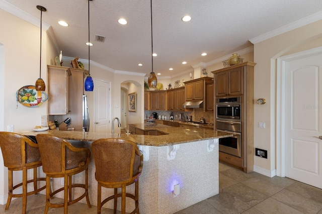 kitchen featuring a breakfast bar, pendant lighting, light stone counters, and crown molding