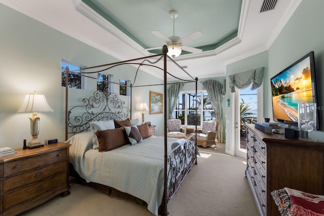 carpeted bedroom featuring access to exterior, a tray ceiling, ceiling fan, and ornamental molding