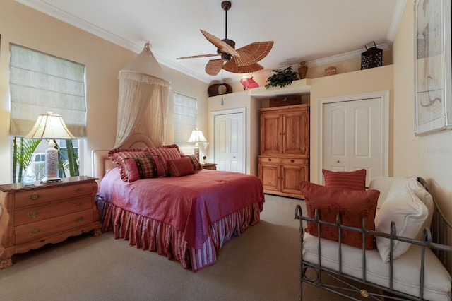 bedroom with ceiling fan, carpet floors, crown molding, and multiple closets