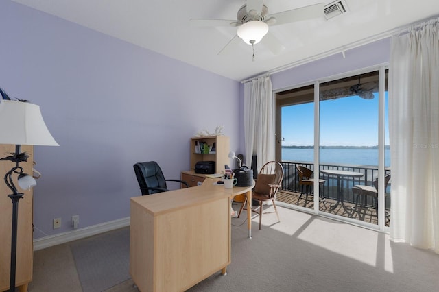 carpeted home office with ceiling fan and a water view