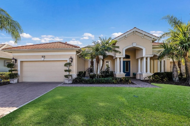 mediterranean / spanish-style home with a tile roof, a front yard, stucco siding, an attached garage, and decorative driveway