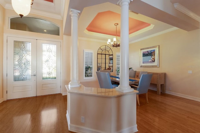 office featuring an inviting chandelier, wood finished floors, a raised ceiling, and ornate columns