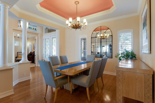 dining area with a wealth of natural light, a chandelier, wood finished floors, and a raised ceiling