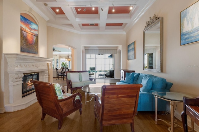 living area featuring coffered ceiling, arched walkways, beam ceiling, a high end fireplace, and wood finished floors