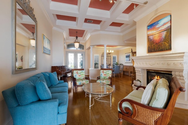 living room with french doors, wood finished floors, an inviting chandelier, and decorative columns