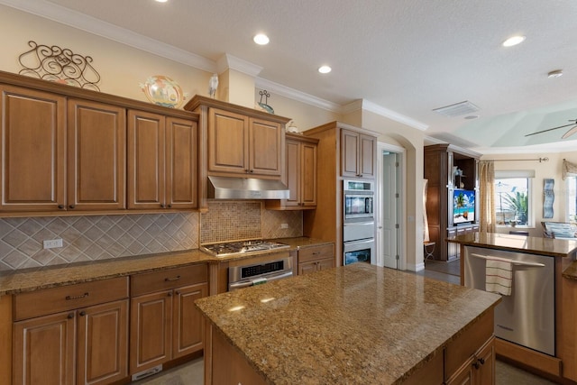 kitchen featuring under cabinet range hood, stone countertops, stainless steel appliances, and a kitchen island