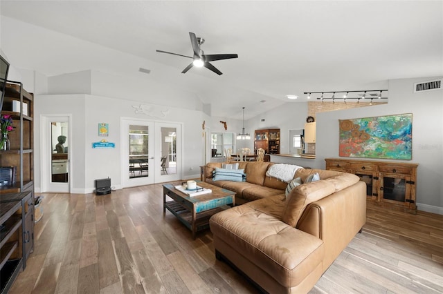 living room featuring french doors, ceiling fan with notable chandelier, light hardwood / wood-style flooring, and lofted ceiling