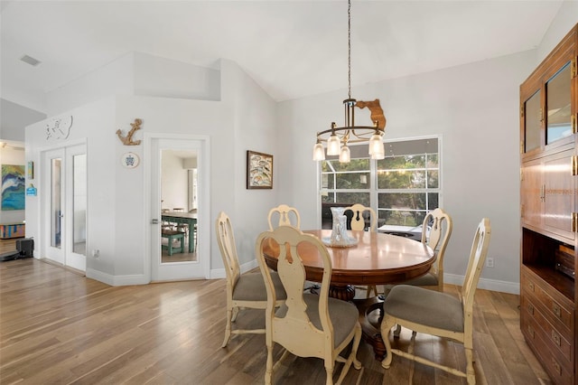 dining space with hardwood / wood-style floors, french doors, and a notable chandelier