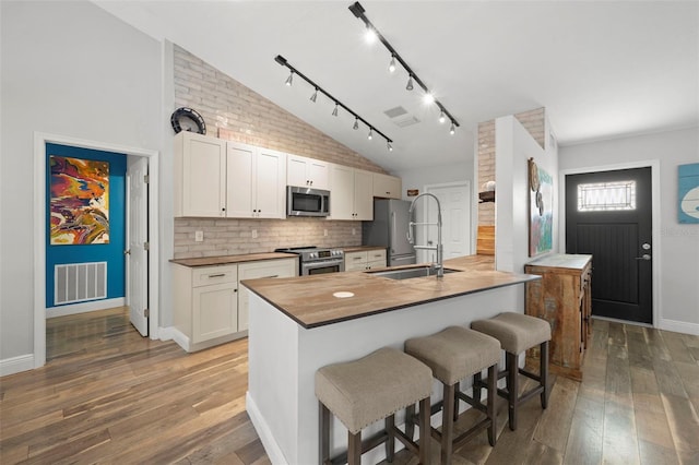 kitchen with a breakfast bar, white cabinets, stainless steel appliances, and sink