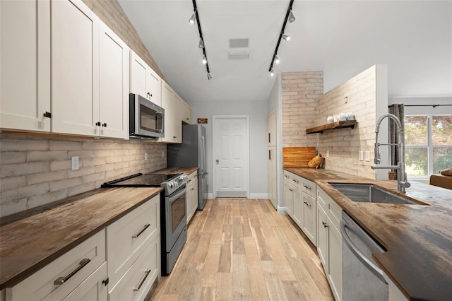 kitchen featuring butcher block countertops, white cabinets, and appliances with stainless steel finishes