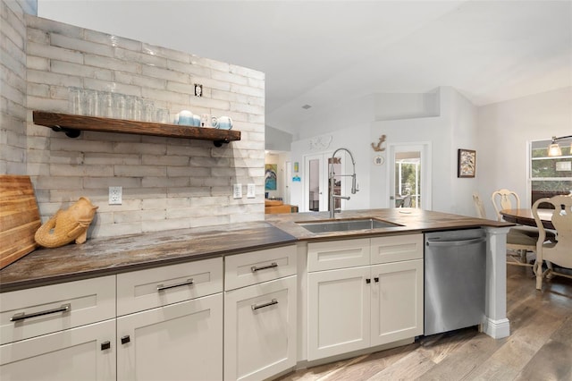 kitchen with butcher block counters, white cabinetry, dishwasher, sink, and light hardwood / wood-style floors