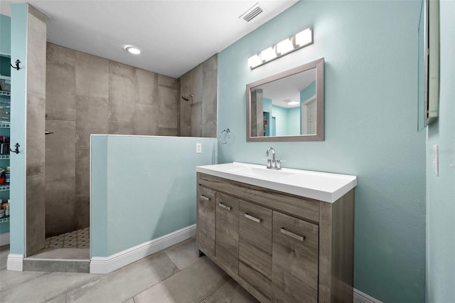 bathroom featuring tile patterned flooring, vanity, and tiled shower