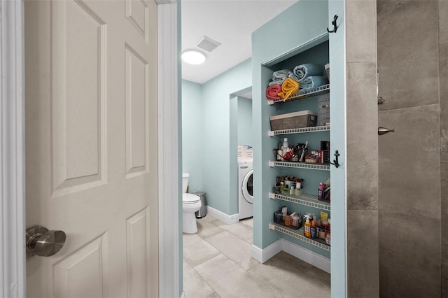 bathroom with tile patterned floors, washer / clothes dryer, and toilet