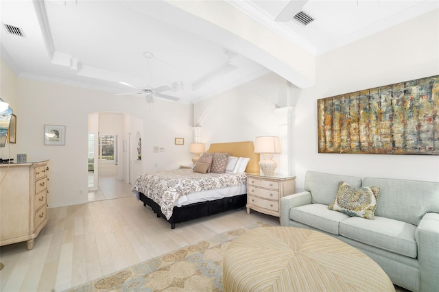 bedroom with a tray ceiling, visible vents, arched walkways, and light wood-type flooring