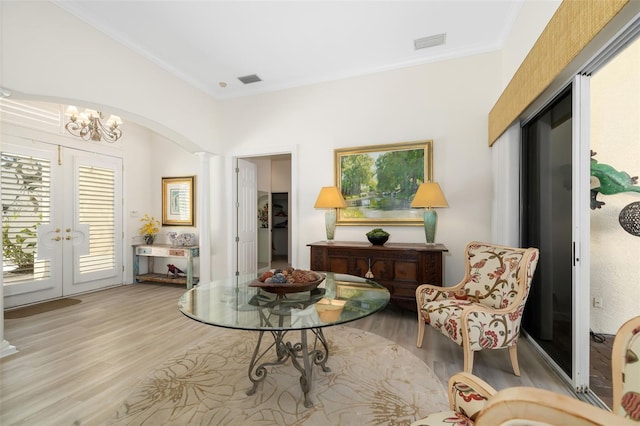 sitting room featuring crown molding, decorative columns, french doors, and light wood-style floors