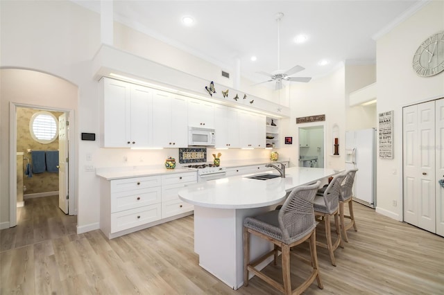 kitchen with ceiling fan, light countertops, a kitchen bar, white appliances, and open shelves