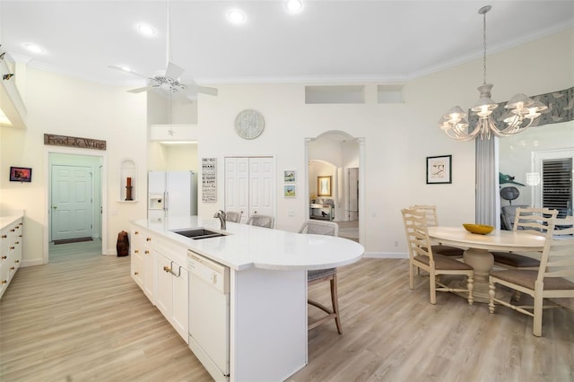 kitchen featuring sink, hanging light fixtures, an island with sink, white appliances, and white cabinets