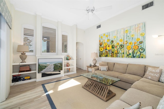 living room featuring visible vents, arched walkways, wood finished floors, and crown molding