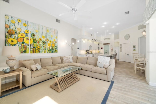 living room with visible vents, light wood-type flooring, and ceiling fan