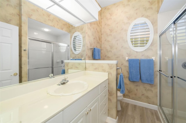 full bath with a shower stall, wallpapered walls, baseboards, toilet, and wood finished floors