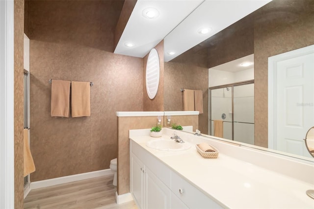 bathroom featuring baseboards, toilet, a stall shower, wood finished floors, and vanity