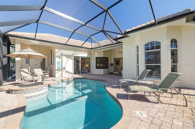 outdoor pool with a jacuzzi, glass enclosure, a ceiling fan, and a patio area