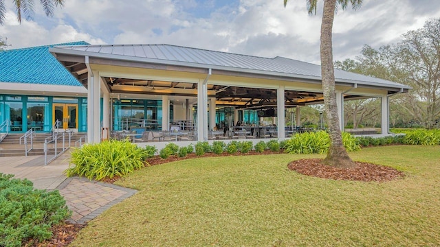 rear view of property featuring a lawn and metal roof