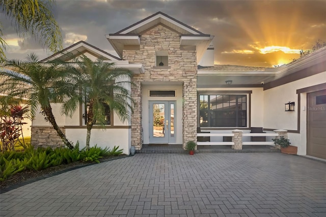 exterior entry at dusk featuring a garage and french doors