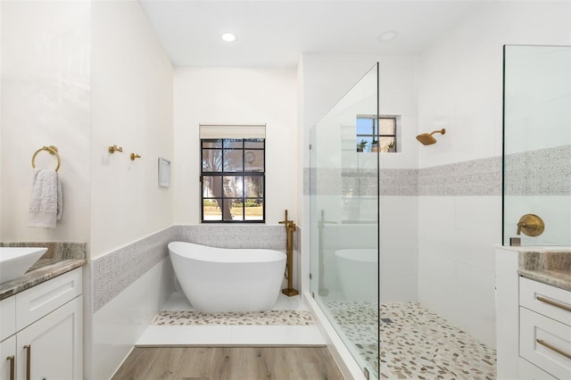 bathroom featuring hardwood / wood-style floors, vanity, tile walls, and shower with separate bathtub