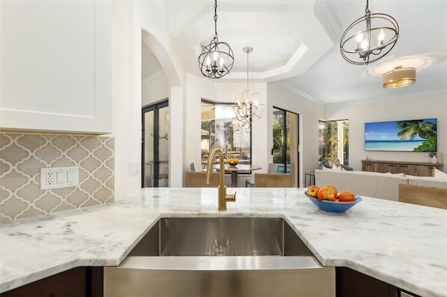 kitchen featuring white cabinetry, light stone counters, crown molding, and pendant lighting