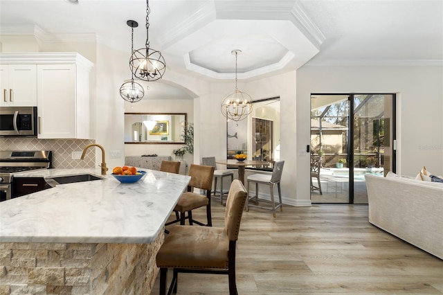 kitchen featuring sink, stainless steel appliances, decorative light fixtures, decorative backsplash, and white cabinets