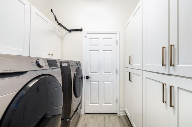 laundry area featuring washer and clothes dryer, cabinets, and light wood-type flooring