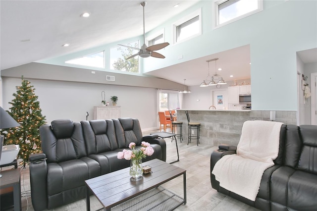 living room with ceiling fan, light hardwood / wood-style floors, and a high ceiling