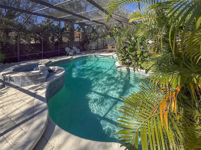 view of pool featuring glass enclosure, a patio area, and an in ground hot tub