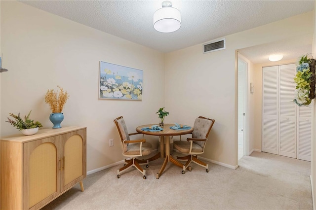 dining space featuring light carpet and a textured ceiling