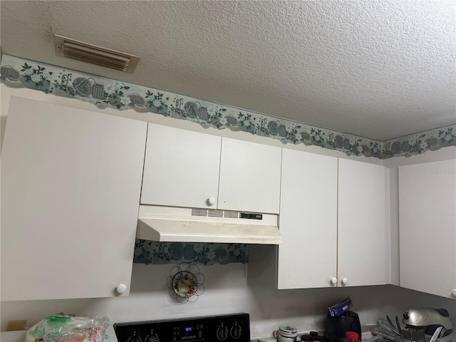 room details featuring white cabinetry, a textured ceiling, and range