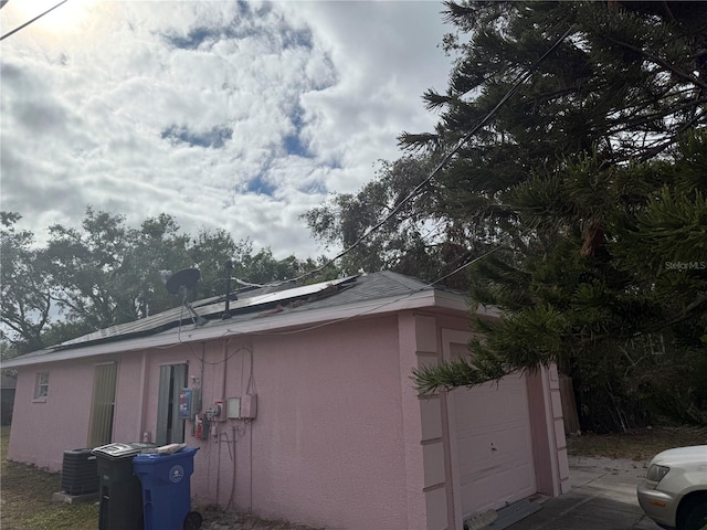 view of home's exterior featuring solar panels, a garage, and central air condition unit